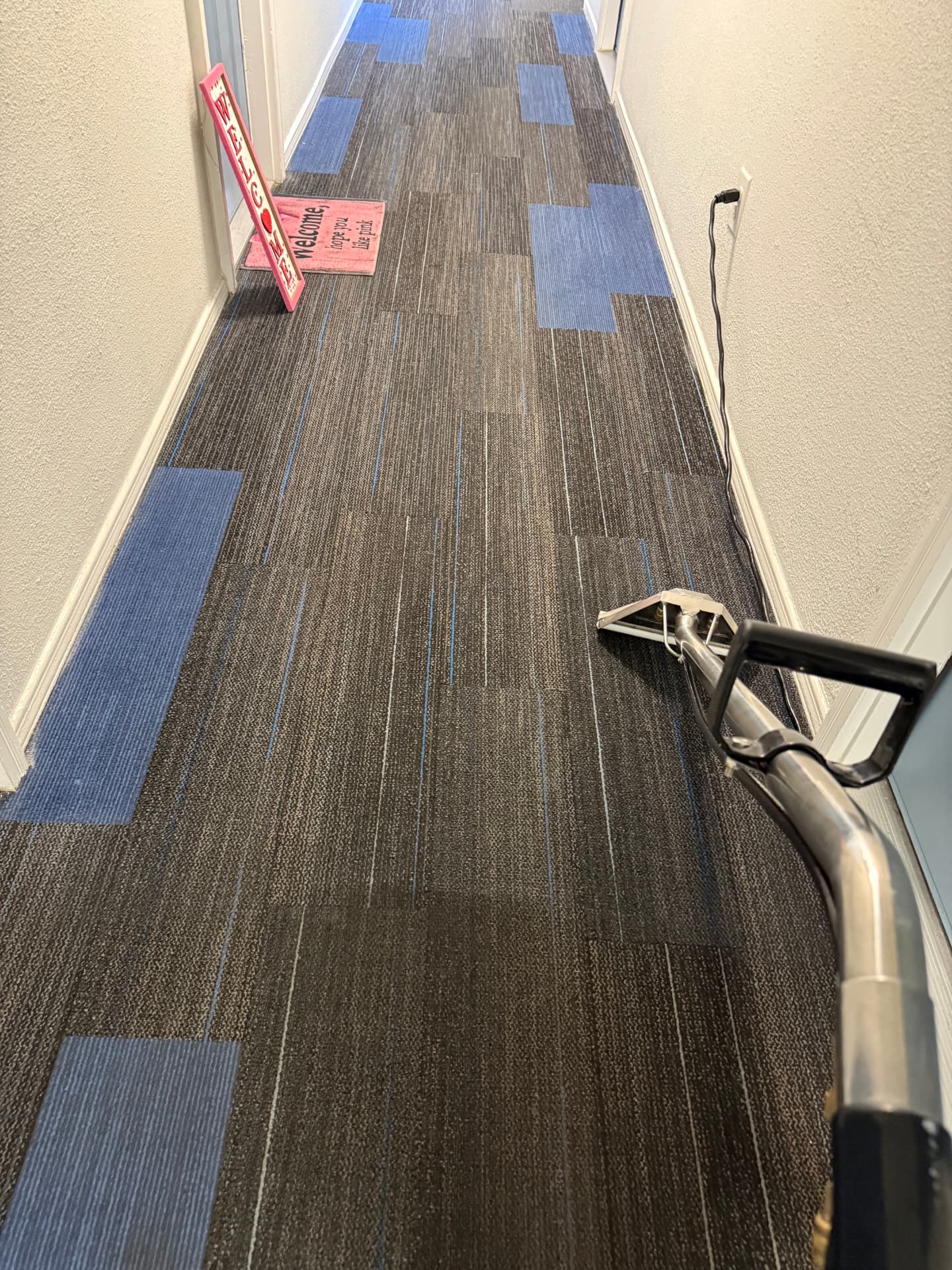 Cleaning wand extracting an office hallway of commercial carpet tiles